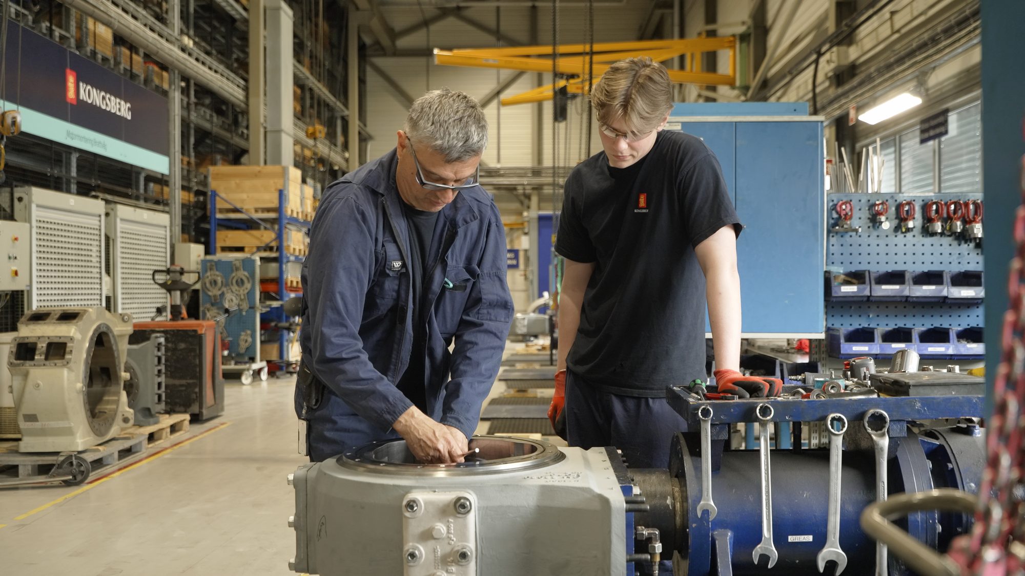 An experienced fitter and a young apprentice working together on a motor unit in the Brattvåg workshop