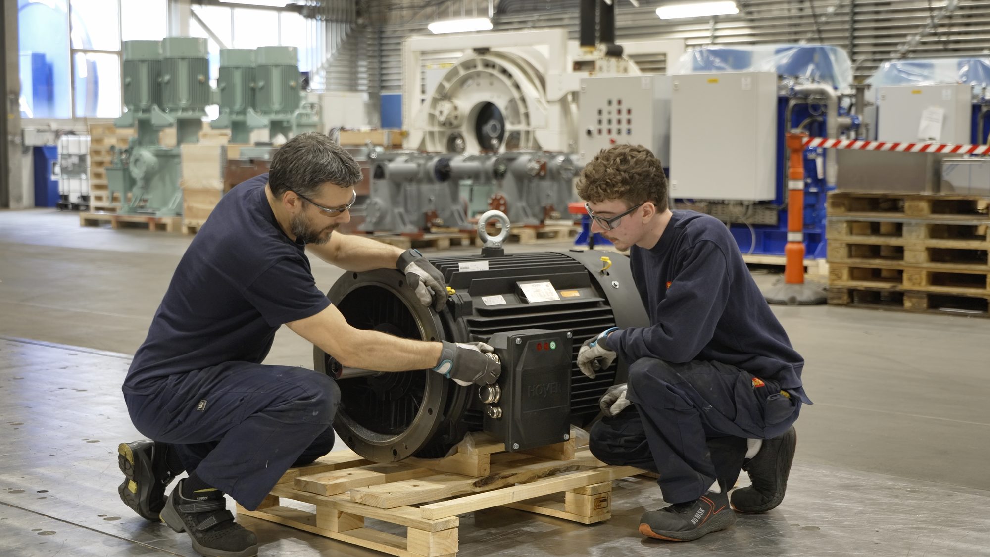 Two fitters preparing a permanent magnet motor for shipment