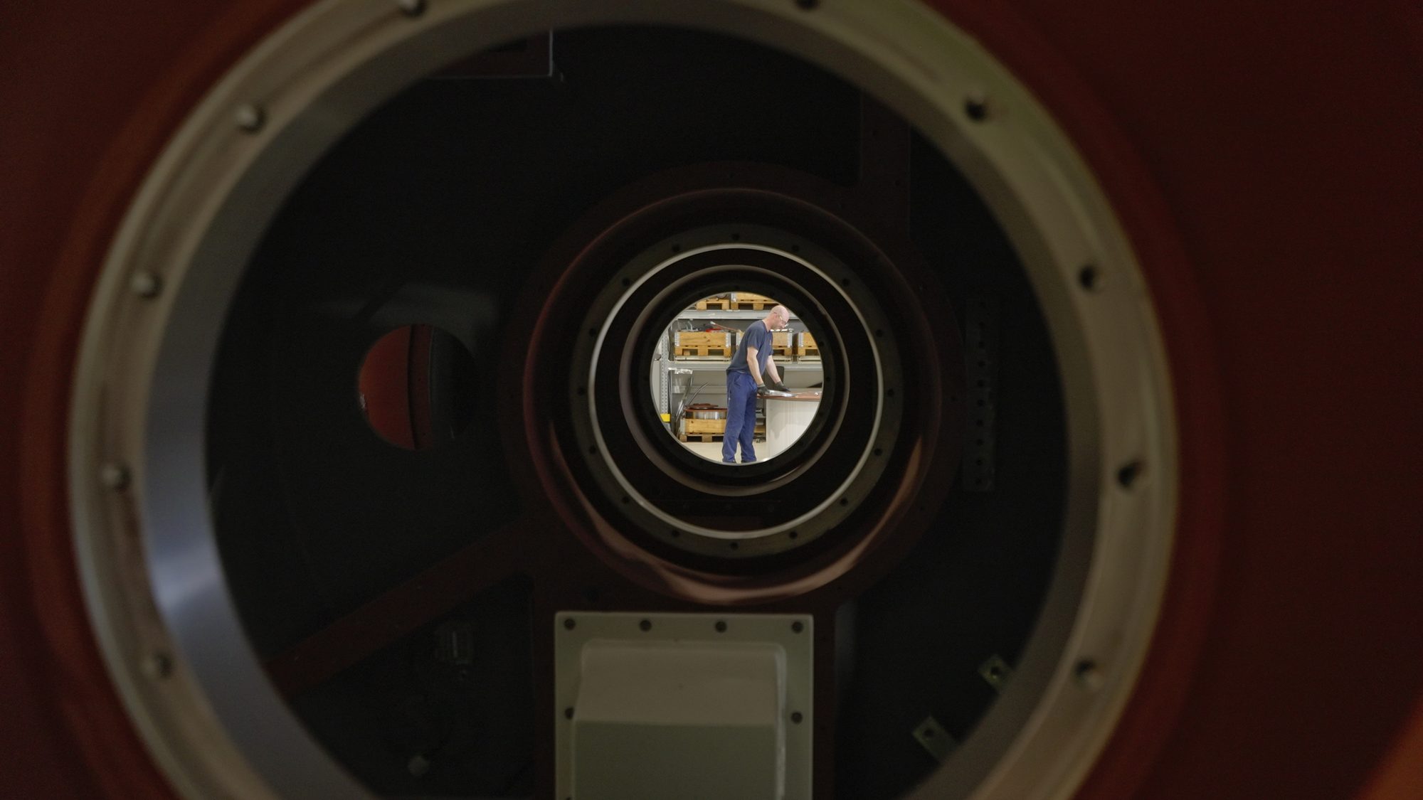 A technician seen through the centre of a large winch housing