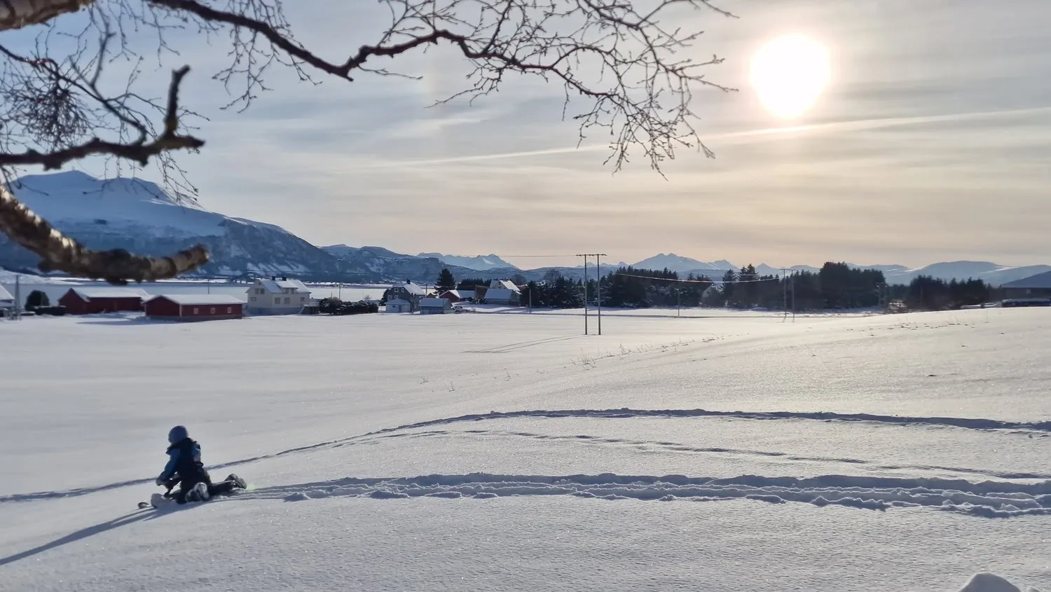 Child sledding across a snowy field at sunset