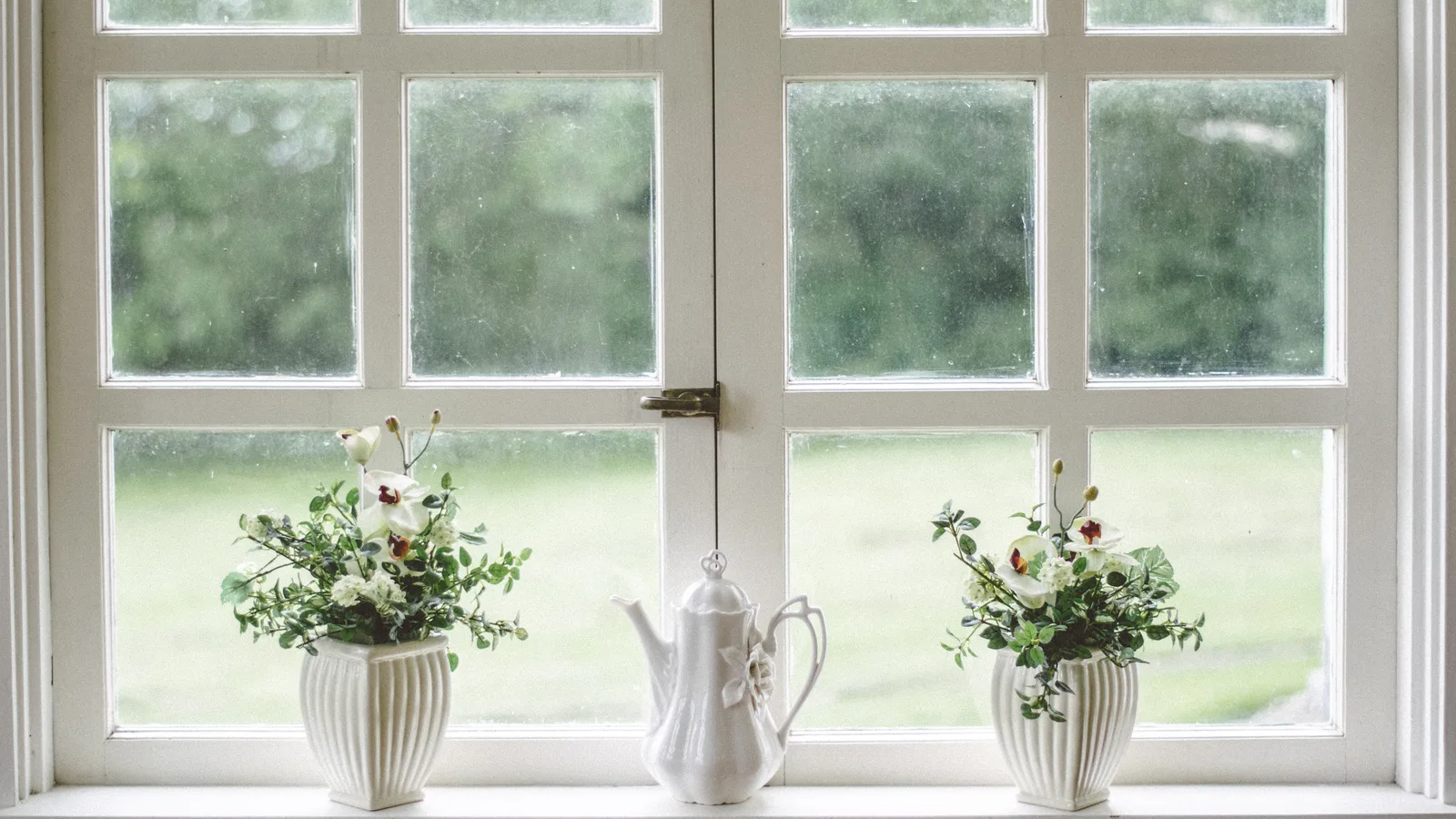 A charming window with white frames decorated with colorful flowers, evoking the warmth of a Norwegian countryside home