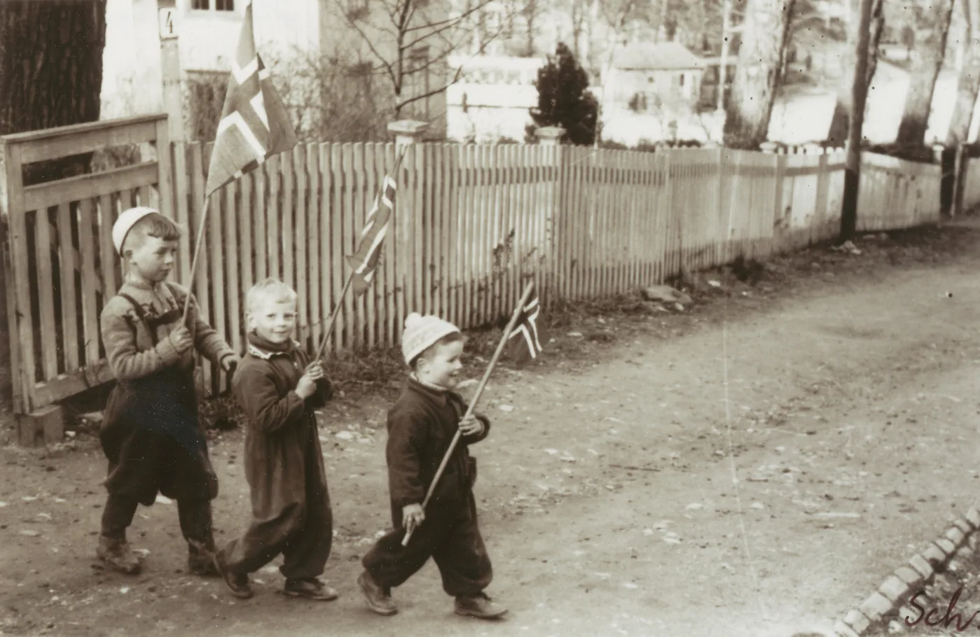 Three young children in Trondheim proudly holding Norwegian flags on Liberation Day, May 8 1945