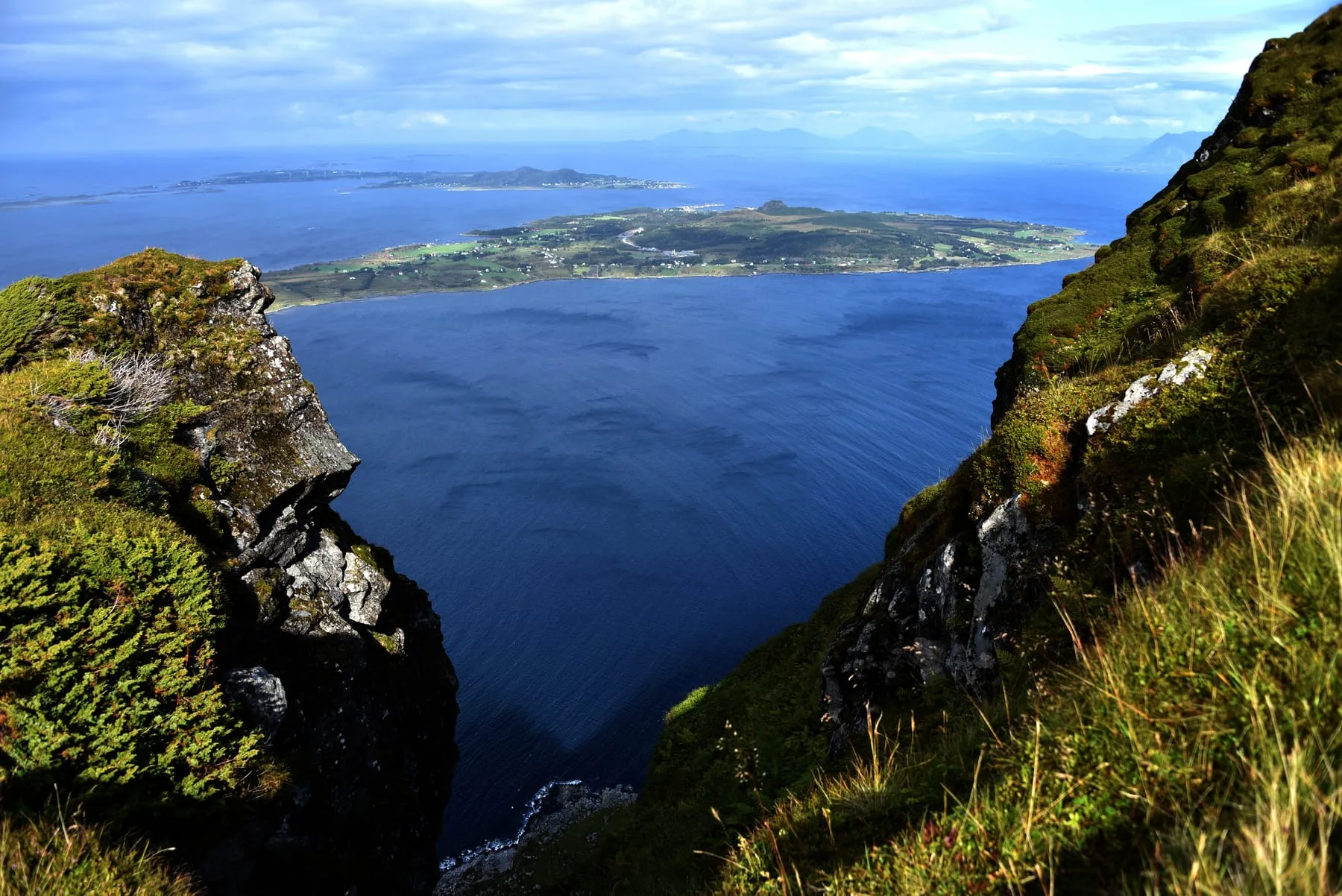 Hikers climbing to the top of Skulen with the island of Fjørtofta visible far below among the ocean and surrounding islands