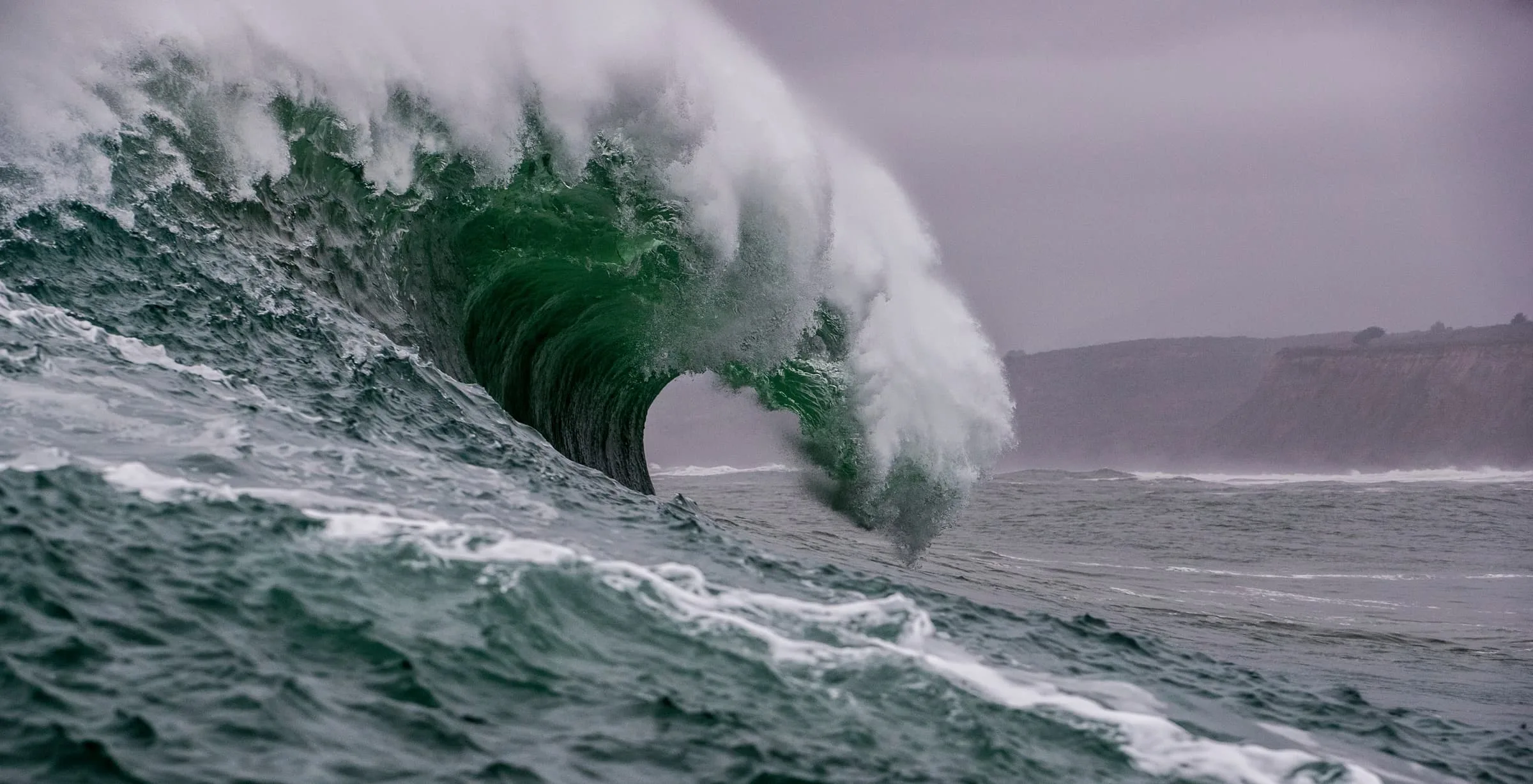 Massive ocean wave cresting against a dark sky, evoking the raw power of natural forces