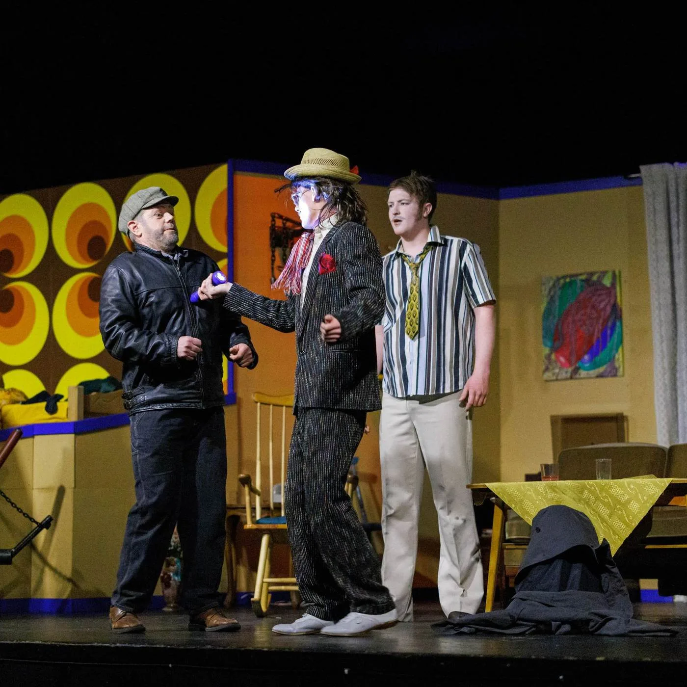 Performers in colorful 1970s costumes on stage during a retro-themed Nordøyane theater show