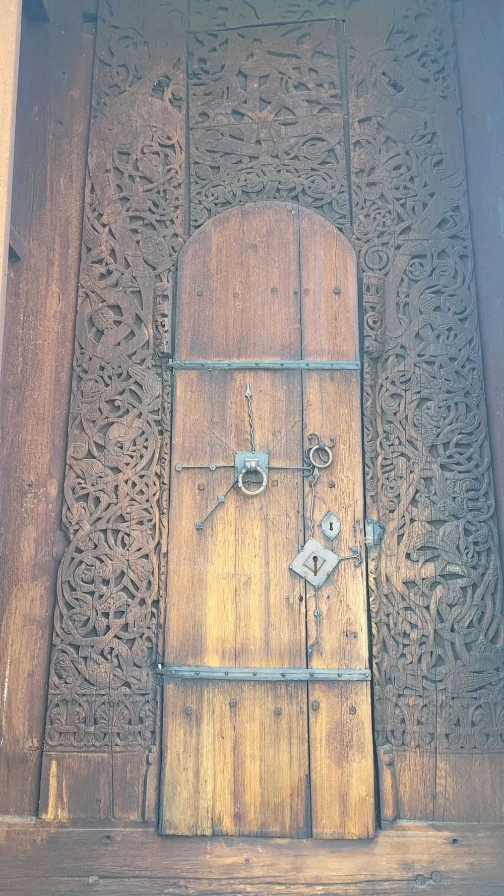 The richly carved west doorway of Torpo Stave Church, framed by intricate dragon-style ribbon work and topped with interlaced beasts