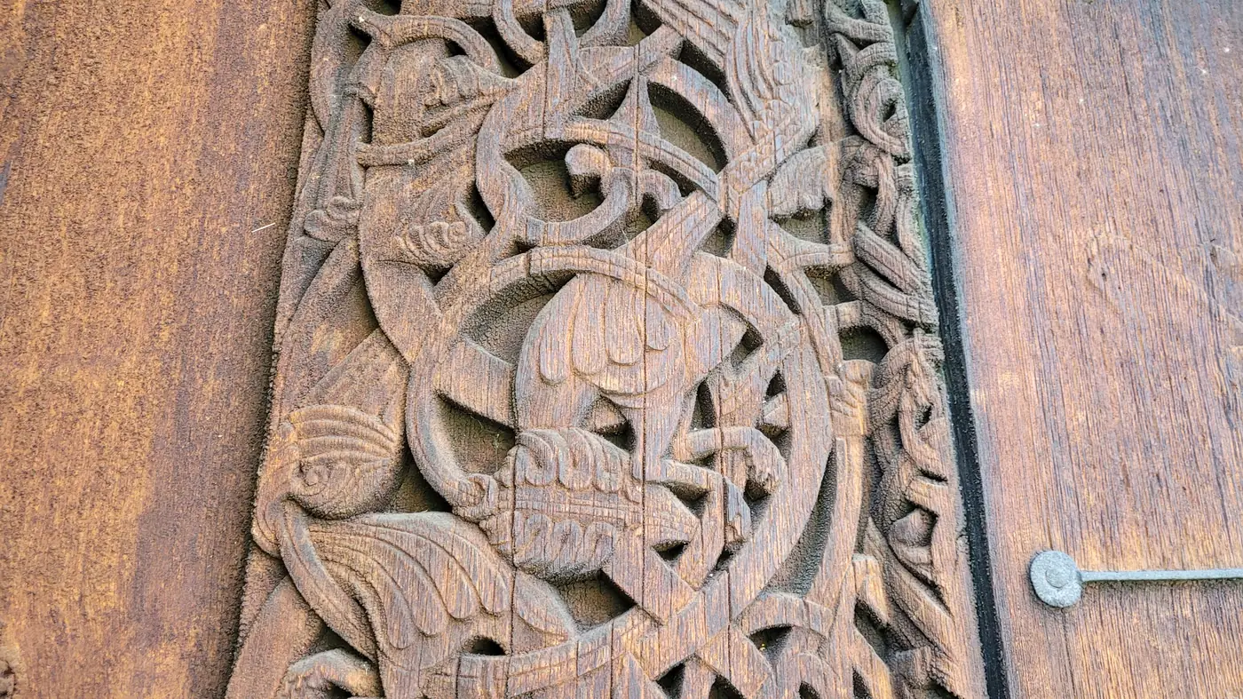 Close-up of a dragon-style carving on Torpo Stave Church: interlaced beasts and ribbon ornament cut deep into oak