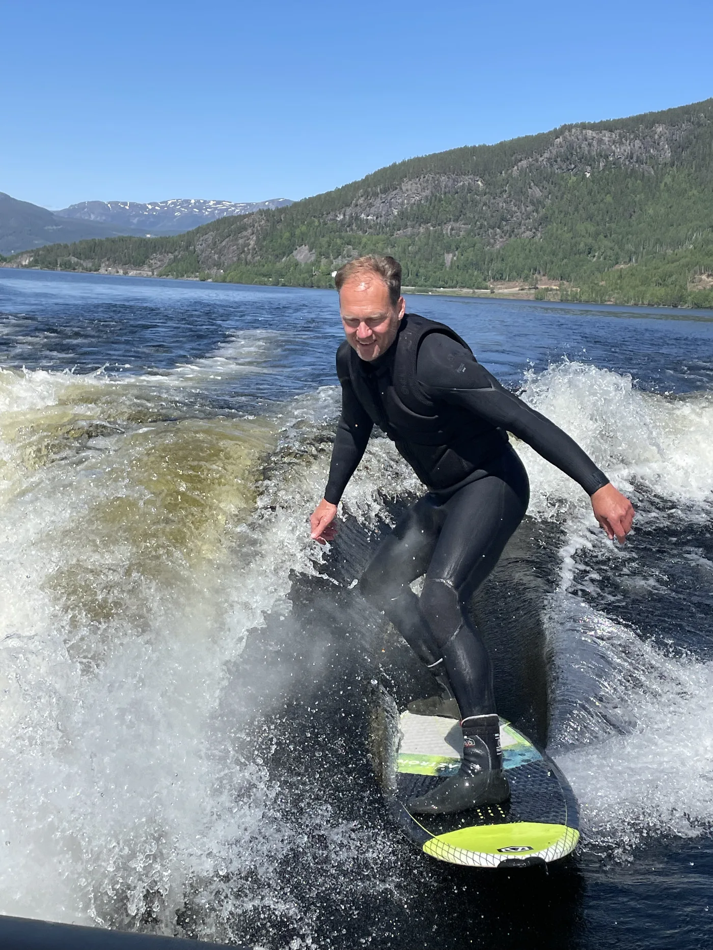 A wakesurfer rides a boat wake on the calm waters of lake Krøderen in Hallingdal, Norway