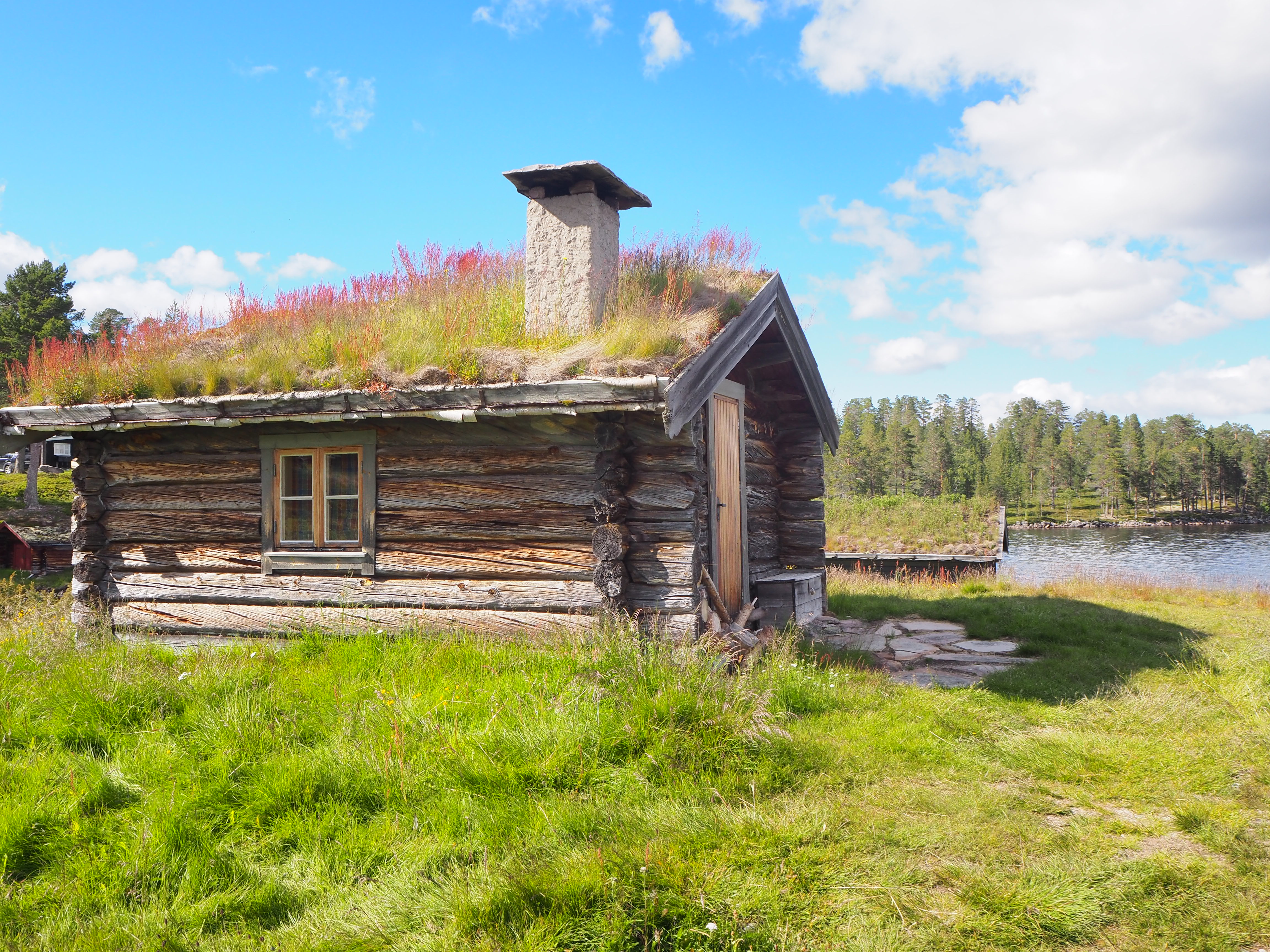 A single hand-hewn log bu at Fiskevollen — door, small window, sod roof