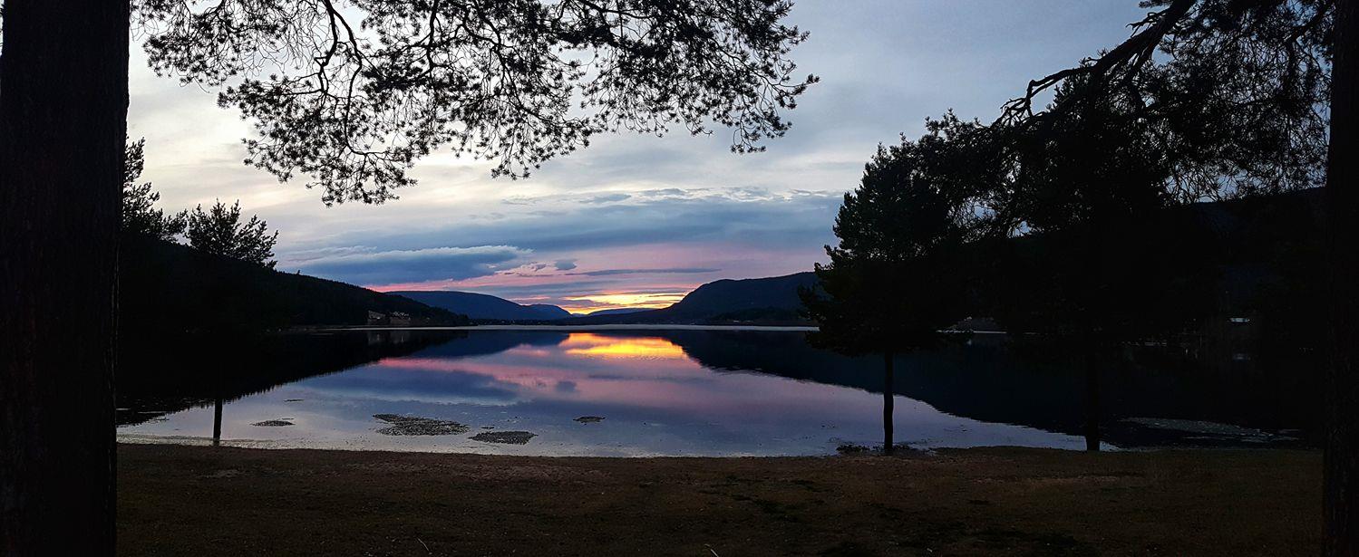 Sunset over Storsjøen at Harrvika — pink and purple sky reflected in still water, pine trees framing the view